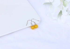 Detail of yellow agate bead earrings with silver hooks on minimalist floral backdrop