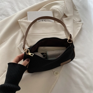 Minimalist black nylon underarm bag with brown strap and golden zipper shown from above