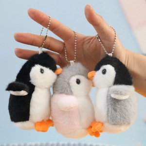 Detailed view of three soft plush penguin keychains with metal chains in various colors