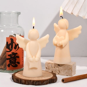 Detail of angel scented candles with heart and star motifs on rustic wood base