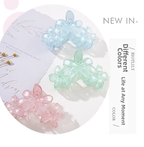 Detailed macro view of three 3D floral hair claws in blue, green, and pink frosted acrylic