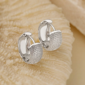 Vue macro de boucles d'oreilles créoles argentées texturées sur fond de pierre naturelle