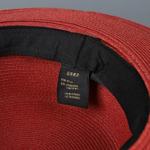 Detailed macro view of the 57cm size label and inner black sweatband of red straw hat