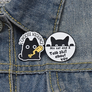 Funny cartoon black cat enamel pins with witty text on denim jacket background