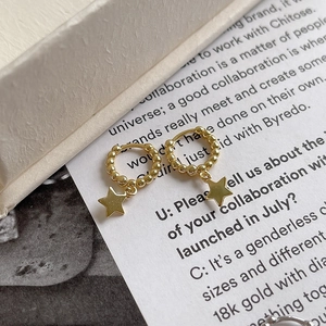 Macro view of gold S925 sterling silver hoop earrings with bead design and star pendant