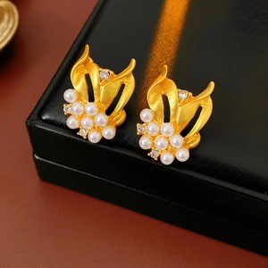 Detail of vintage gold pearl earrings with zircon stones on black leather jewelry box