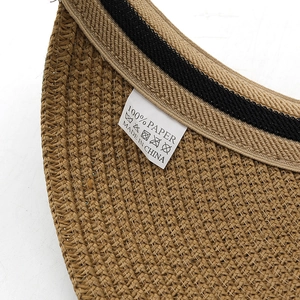 Détail du bord du chapeau en paille tressée montrant l'étiquette 100% papier et les conseils