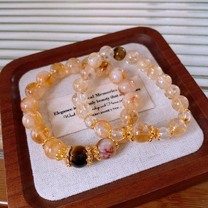 Macro view of golden rutilated quartz and tiger eye beaded bracelets on wood tray