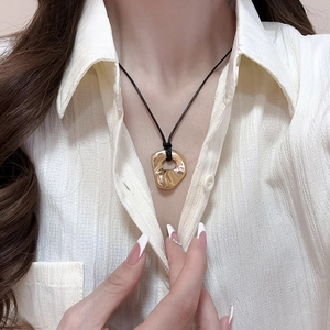 Close-up of golden irregular double heart pendant necklace worn on a white shirt
