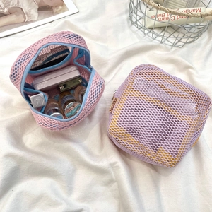Detailed view of pink and purple mesh cosmetic bags with lipsticks on white fabric
