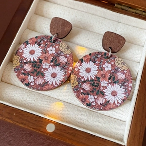 Detailed view of vintage wooden earrings with floral patterns in a jewelry box