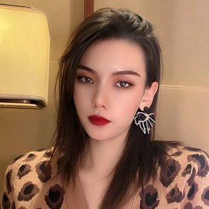 Close-up of black bow earrings with sparkling colorful rhinestones on female model