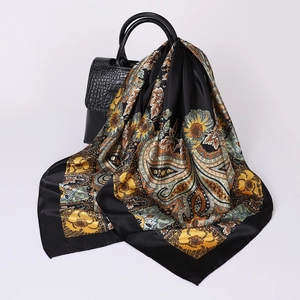 Detailed drape of paisley print silk scarf over a black crocodile pattern handbag