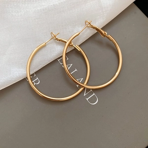 Detailed close-up of golden minimalist hoop earrings with high-gloss metallic finish