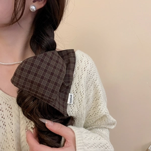 Detail of a brown plaid double-layered scrunchie with a handmade tag on hair