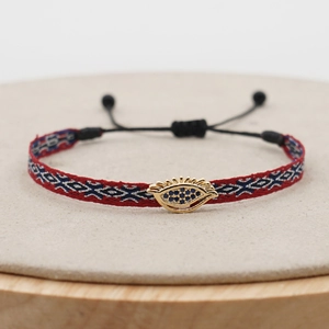 Detailed macro view of woven Evil Eye bracelet with blue micro-crystals and red strap