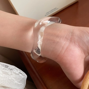 Detail of minimalist wavy resin bangle showing irregular shape and warm translucent finish