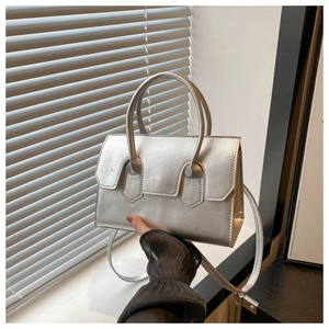 Close-up of silver structured handbag with top handle and decorative flap details