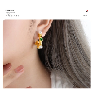 Gros plan de boucles d'oreilles vintage avec pierres vertes et perles sur un modèle
