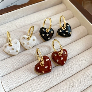 Detailed macro view of enamel heart earrings in white black and red with inlaid crystals