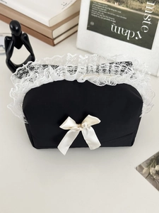 Détail du sac de rangement noir avec bordure en dentelle et nœud orné d'une perle