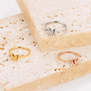 Frosted butterfly stainless steel rings in gold, silver, and rose gold on stone steps