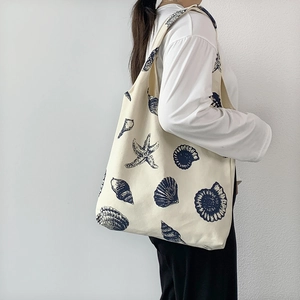 Canvas shoulder bag with blue shell print shown worn as a crossbody for daily use