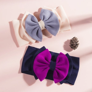Detail of waffle knit fabric on baby headbands featuring large bicolor bows and texture