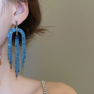 Gros plan de boucles d'oreilles à pompons en strass bleus avec retombée élégante