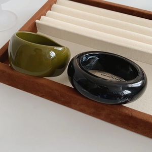 Macro detail of wide marble pattern and olive green resin bangles in jewelry tray