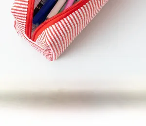 Detail view of a large seersucker pencil case with red stripes and colorful pens