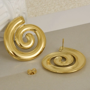 Detailed view of golden spiral geometric stud earrings with metal backings on props