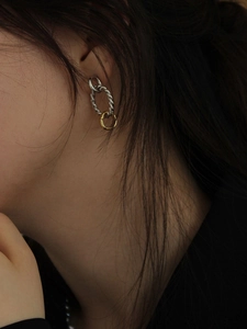 Detailed view of intertwined silver and gold twisted rope texture hoop earrings on model
