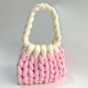 Close-up of pink and cream hand-knitted chunky yarn bag with textured weave and soft handle