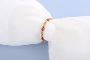 Macro dettaglio di un anello a catena dorata con eleganti accenti in resina rossa