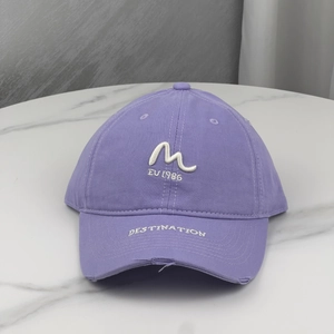 Detail of purple washed cotton baseball cap with DESTINATION embroidery and distressed holes