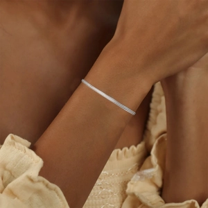 Detailed view of layered 925 sterling silver snake chain bracelet worn on a female wrist