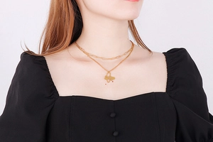 Detail shot of a double-layered gold necklace with a hollow butterfly pendant on a model
