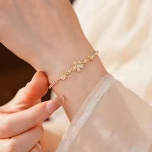 Dettaglio di un bracciale a fiori dorati con zirconi brillanti indossato dal modello