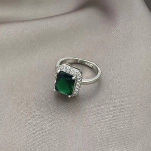 Macro-opname van smaragdgroene ring met zirkonia halo op een grijze zijden achtergrond