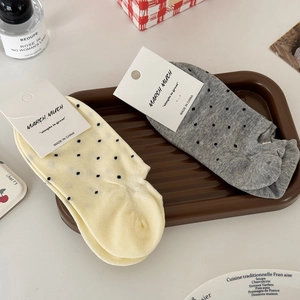 Chaussettes en coton à pois jaunes et gris présentées sur un plateau en bois élégant