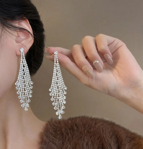 Close-up of sparkling silver tassel earrings with long rhinestones on elegant female model
