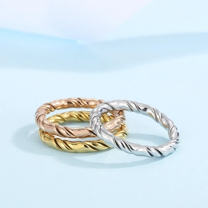 Detailed view of three twisted texture rings in gold, rose gold, and silver finishes