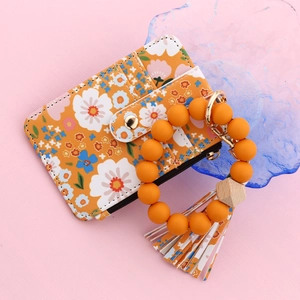 Détail macro du porte-clés bracelet en perles silicone fleuri avec porte-cartes jaune
