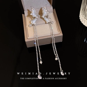 Boucles d'oreilles nœuds argentées avec pampilles, strass et perles sur un écrin