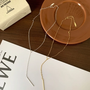 Detailed view of gold and silver Y-shaped necklaces on a wooden table with ceramic decor