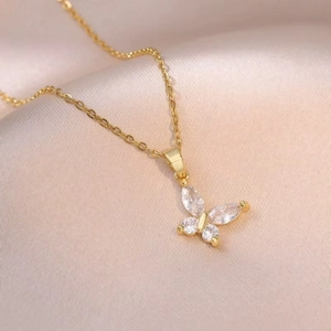 Detailed close-up of a golden butterfly pendant with sparkling zircons on pink satin fabric
