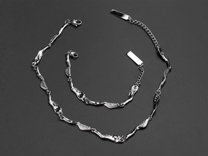 Detailed macro view of silver irregular wave link bracelet and necklace with lobster clasp