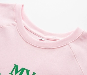 Détail de l'encolure du t-shirt en tricot rose clair avec coutures et étiquette taille L