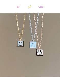 Detailed view of three square smile pendants in gold, silver, and rose gold finishes